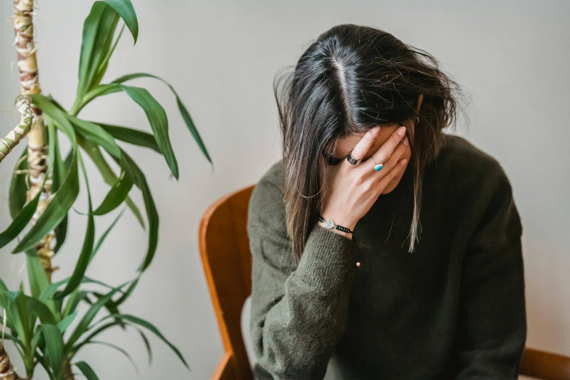 A woman sitting on a chair with her head in her hand, appearing tired or overwhelmed.