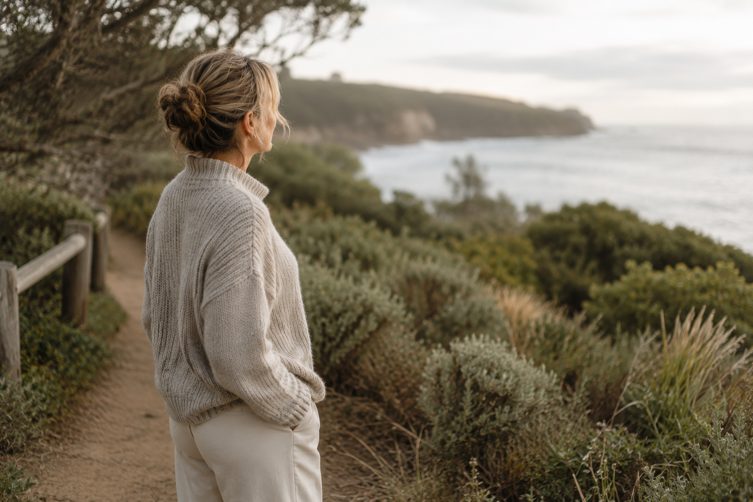 Woman in a knit sweater overlooking the coast on a peaceful winter day.