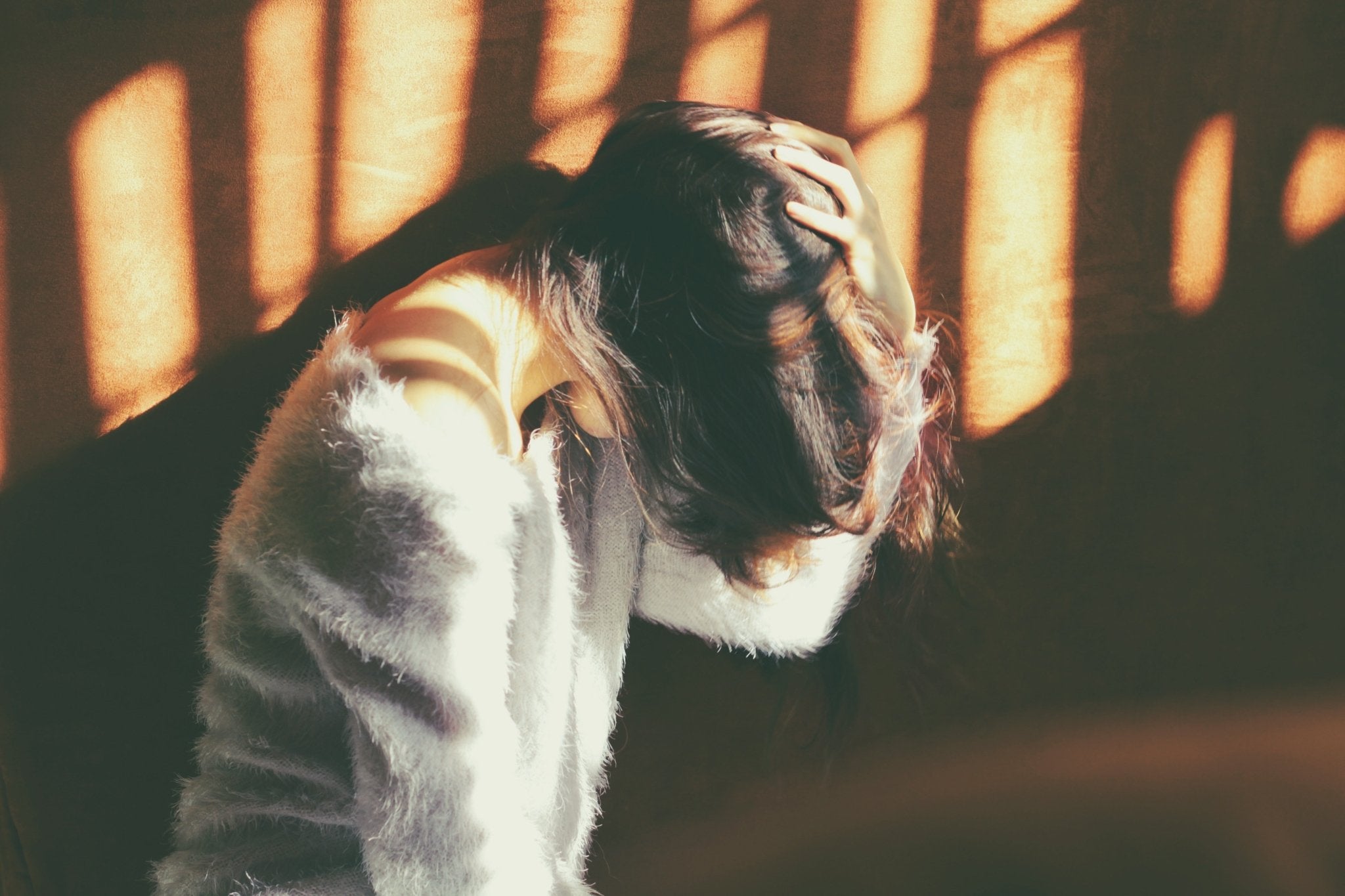 Woman holding head with hair hanging over face