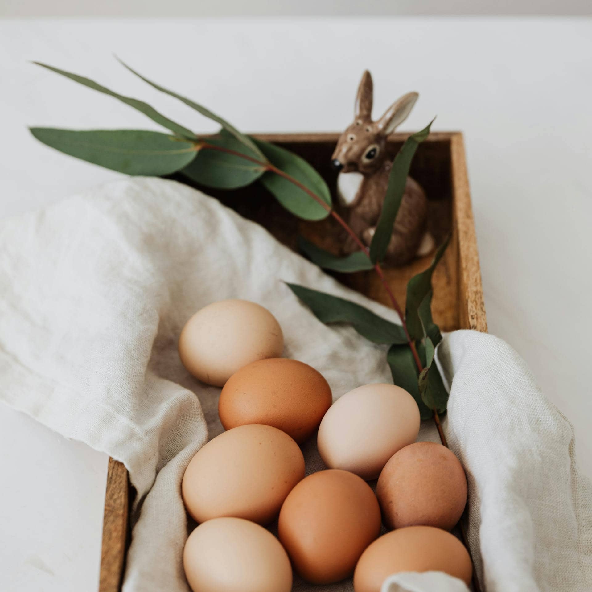 Brown and white eggs arranged in a wooden tray, representing a natural source of collagen-building nutrients like protein and amino acids.