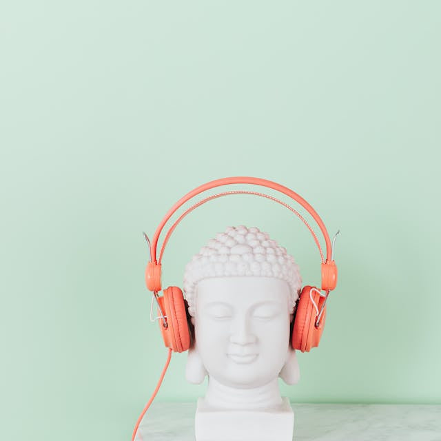 statue of a bust on a marble table wearing orange headphones. 