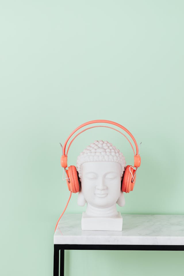 statue of a bust on a marble table wearing orange headphones. 