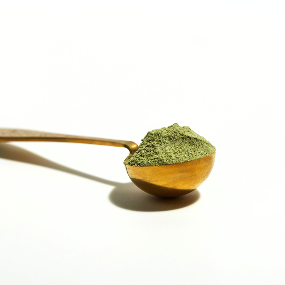 gold spoon with heaped green powder flourish