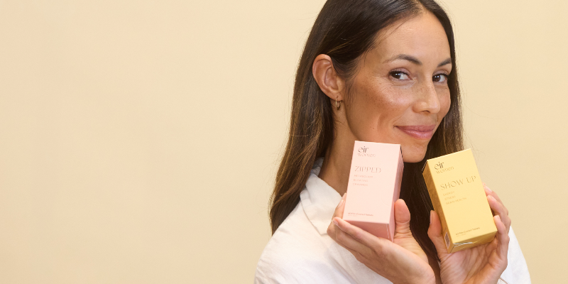 Woman holding two skincare products against a beige background