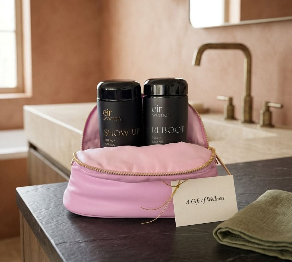 Two black glass bottles labeled 'Show Up' and 'Reboot' in a pink pouch on a bathroom counter.